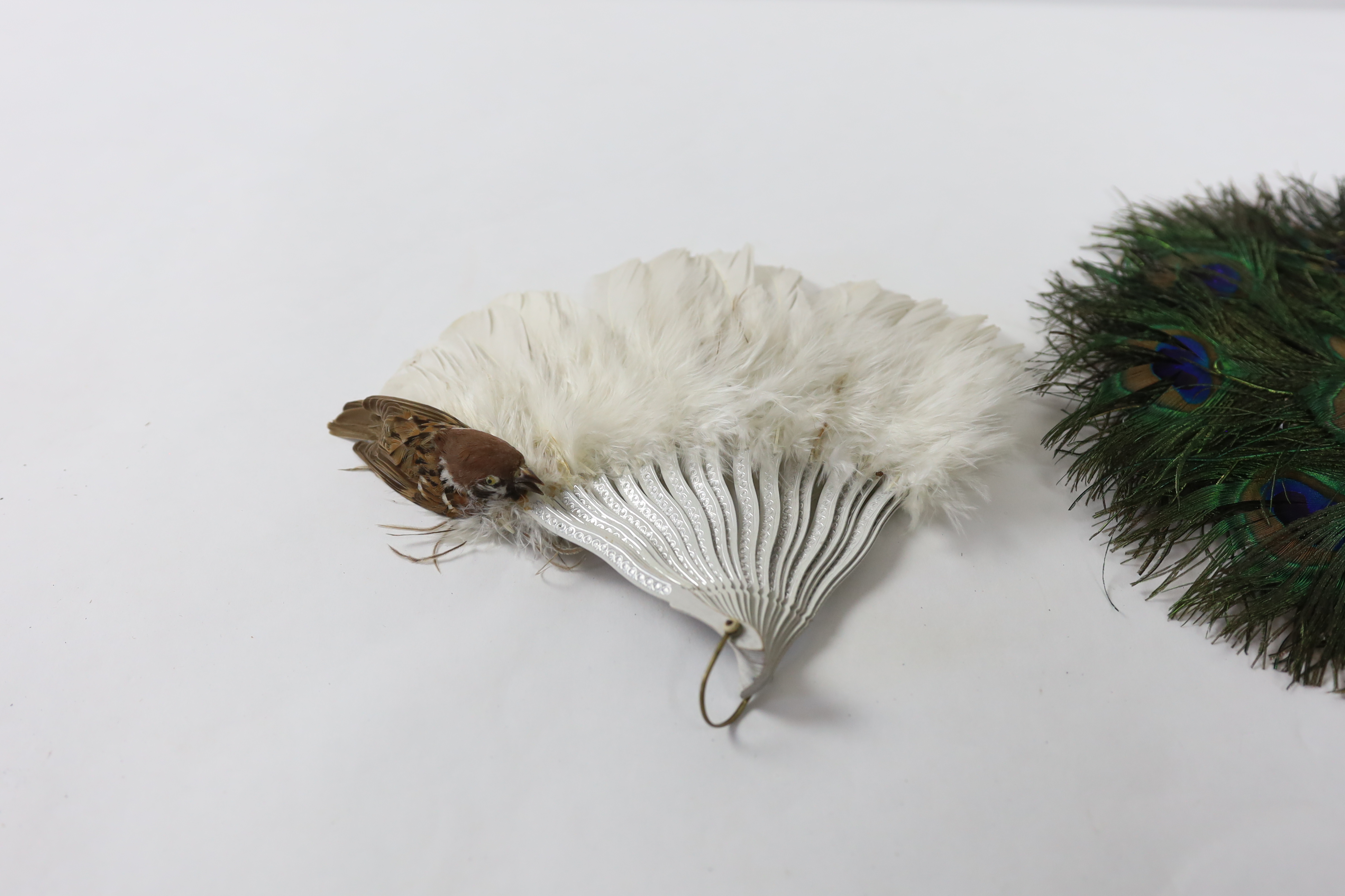 Two Edwardian early 1920’s feather fans with unusual bird decoration together with a peacock fan, one with cream Bakelite handle and guards, feather leaf and bird decoration, the other with silver painted guards, feather